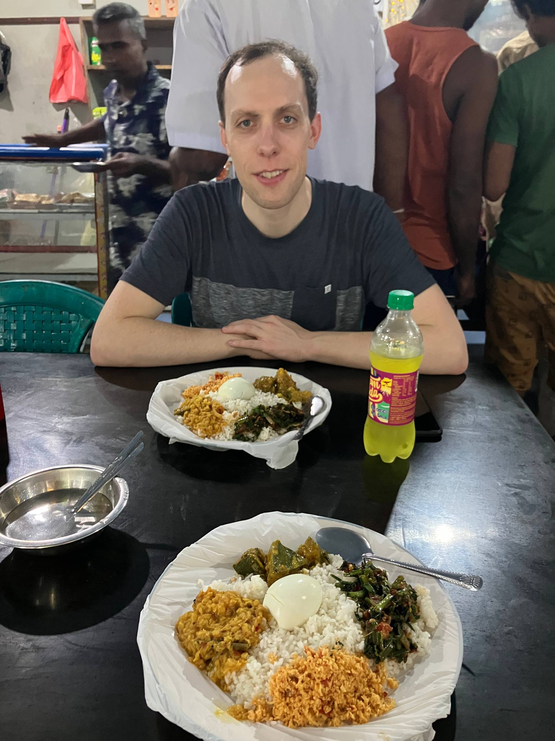Ein Teller mit Reis, Currygerichten und Ei auf einem Tisch in einem einfachen Restaurant.